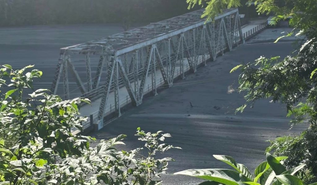 Damaged motorable bridge over Budhi Gandaki river showing collapsed concrete span while steel truss stands